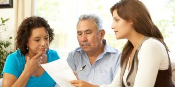 An image of a worker pointing at a paper while showing it to an elderly couple.